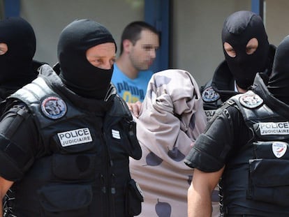 Policías custodian a una mujer tras registrar el piso de un sospechoso en Saint-Priest.