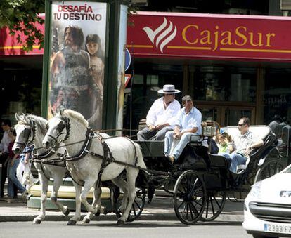 Unos turistas pasean, el pasado lunes, en coche de caballos frente a la sede central de Cajasur en Córdoba.