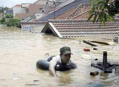 Un residente flota sobre un neumático en un barrio de Yakarta anegado por las aguas.