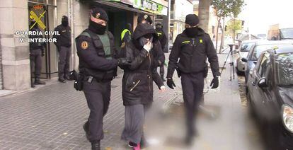 Dos agentes trasladan a una detenida por captar yihadistas, en Catalu&ntilde;a.
