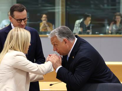 Viktor Orbán besa la mano de la primera ministra italiana, Giorgia Meloni, en presencia del primer ministro de Polonia, Mateusz Morawiecki, este jueves en Bruselas.