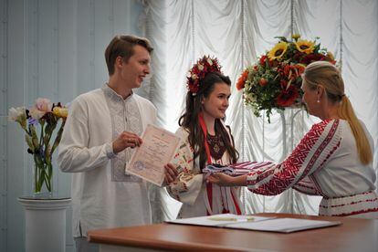Una funcionaria entrega en Kiev a los novios, Oleksii, de 24 años, y Kristina, de 22, el certificado y una tela tradicional con bordados.