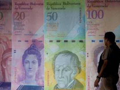 Un hombre camina frente a unos afiches de billetes venezolanos en el Banco Central de Venezuela en Caracas. EFE/Archivo
