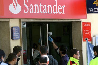 Un policía toma huellas en la puerta de la entidad bancaria.