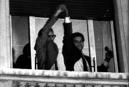 Alfonso Guerra levanta la mano de Felipe González asomados ambos a una ventana del hotel Palace de Madrid tras la victoria del PSOE en las elecciones legislativas.