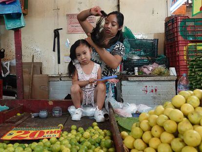 Una mujer peina a su hija en el mercado de la Merced, en Ciudad de México.