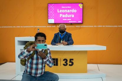 A visitor to the Guadalajara Book Fair takes a photo with Leonardo Padura during a book signing.