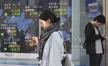 Dos personas miran sus teléfonos en Tokio. 