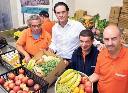 Eduardo Petrossi, consejero delegado de Mahou-San Miguel, con las personas que preparan las cestas de frutas y verduras que cultivan en la Fundación Juan XXIII, donde es voluntario.