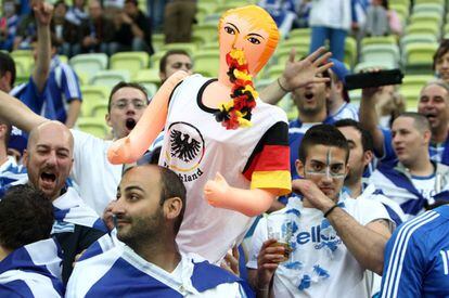 Aficionados griegos llevan una muñeca hinchable vestida con una camiseta de Alemania con el nombre de la canciller Angela Merkel.