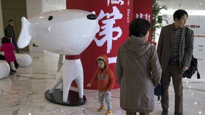 Un nuño pasea junto a la mascota del gigante chino del comercio electrónico JD.Com.