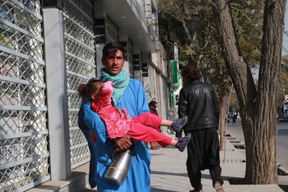 Un hombre abandona con una niña en brazos los alrededores del hospital tras las dos explosiones, este martes en Kabul.