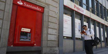 Un hombre espera junto a un cajero automático de Banco Santander.