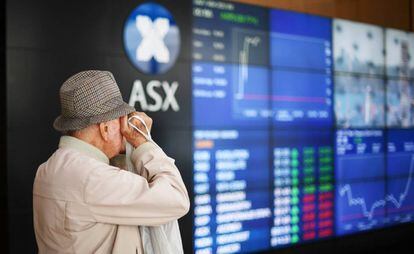 Un hombre mira los monitores que informan de los valores del mercado bursátil australiano ASX, en una imagen de archivo.
