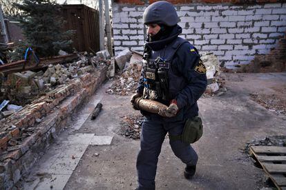 Un empleado de los servicios de emergencia de Ucrania retira un proyectil de artillería sin estallar de los restos de un chalé a las afueras de la ciudad de Járkov.