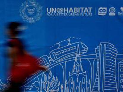 Una mujer camina frente a un cartel alusivo al Foro Urbano Mundial en Medellín (Colombia).