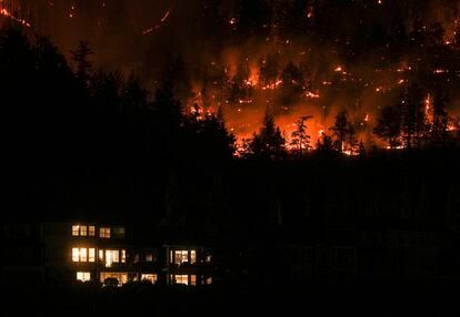 El incendio de McDougall Creek, Canadá, avanza por una ladera de una montaña por encima de una casa, este viernes. 