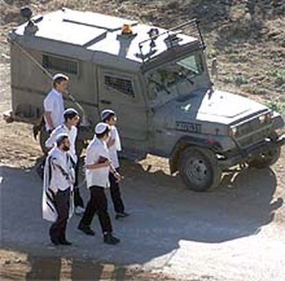 Los soldados protegen en Hebrón a un grupo de colonos en su camino a las oraciones del sábado.