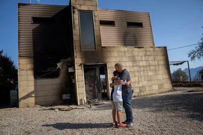 Alex Codonyer abraza a su hijo frente a su vivienda quemada, un día después del incendio.