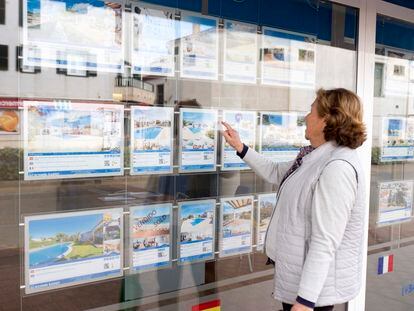 Una mujer mira anuncios de casas en una inmobiliaria de Menorca.