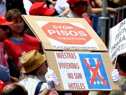 Un hombre sostiene un cartel bajo el lema "stop pisos turísticos" durante la manifestación del Primero de Mayo, en Madrid.