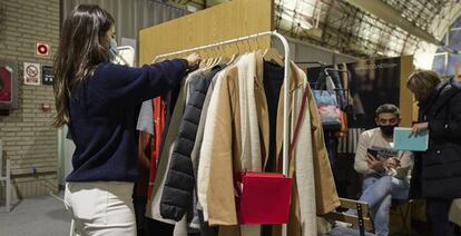 Una mujer ordena ropa en un puesto de comercio. 