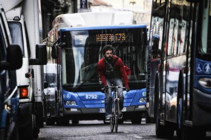 Un hombre circula en bicicleta entre el tráfico pesado por la Carrera de San Jerónimo.