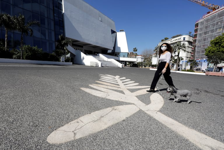 Una mujer lleva una máscara ante un símbolo de la Palma de Oro pintado en el paseo de la Croisette, donde se celebra el Festival de Cannes, en Francia, el pasado 18 de marzo .
