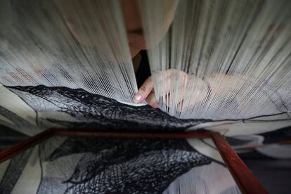 Marta Soria revisa su trabajo en un espejo mientras teje a mano un tapiz, en la Real Fábrica de Tapices de Madrid.