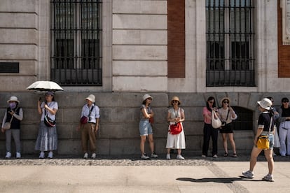 Varios turistas resguardan del calor en la sombra este lunes en Madrid.