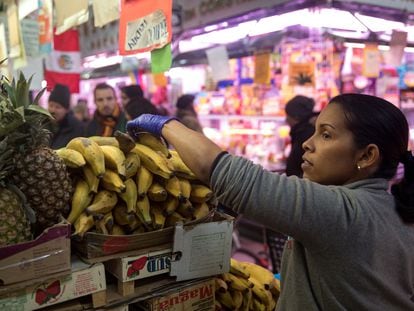 Una trabajadora manipula los productos de su frutería en el Mercado de Maravillas, en Madrid.