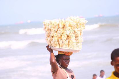 Una vendedora ambulante comercializa palomitas en una playa de Ghana.
