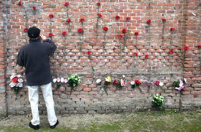 Un hombre pone claveles en las tapias del cementerio la Almudena de Madrid, en las que fueron fusiladas 2.663 personas.