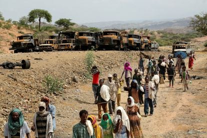 Aldeanos regresan de un mercado en Yechila, región de Tigray, junto a vehículos quemados durante el conflicto el pasado 10 de julio.