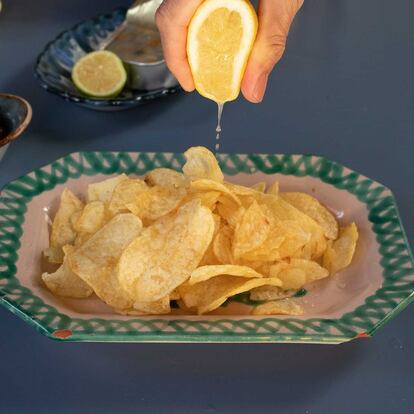 Una persona exprime un limón sobre unas patatas fritas.
