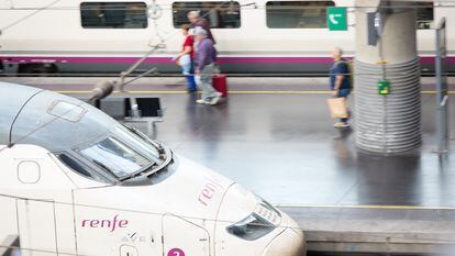 Viajeros con maletas entre trenes de Renfe en uno de los andenes de la estación madrileña de Atocha.