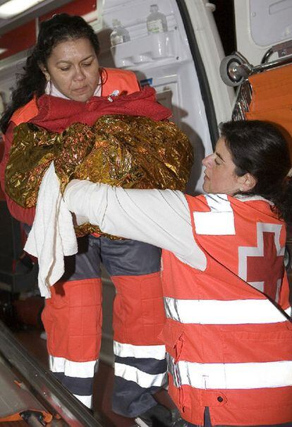 La enfermera de Cruz Roja de Motril Luisa Ferriz (derecha) entrega a una voluntaria a la pequeña Happiness, nacida en una patera en la isla de Alborán.