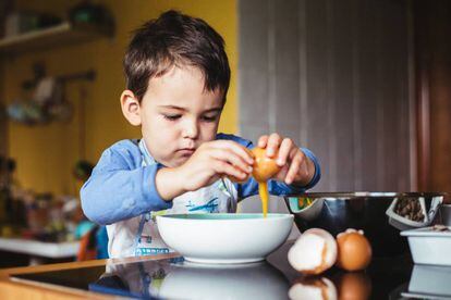 Un niño fríe un huevo. 