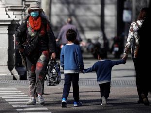 Un par de niños cruzan de la mano de su madre una calle en Madrid. 