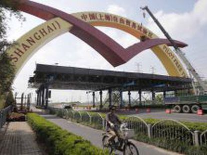 Una mujer en bicicleta pasa junto a un arco que se&ntilde;ala la &quot;Zona de libre comercio de Shangh&aacute;i&quot;, en Shangh&aacute;i (China).