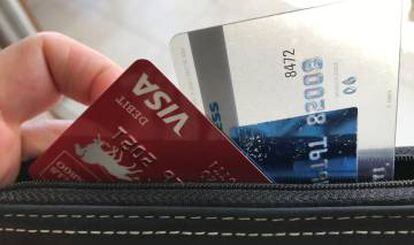 Una persona retira una tarjeta de su bolso de mano.