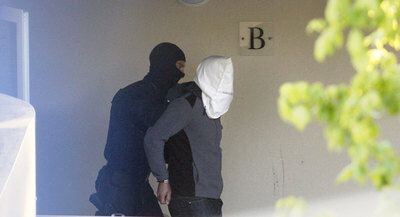 Un policía francés traslada a uno de los presuntos etarras detenidos en una vivienda de Bayona.