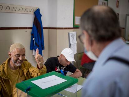 Un integrante de la mesa electoral felicita a un vecino tras ejercer su derecho al voto en la Barriada de Los Pajaritos, en Sevilla.