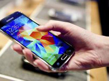 Una mujer sostiene en su mano un tel&eacute;fono inteligente Samsung Galaxy S5. 