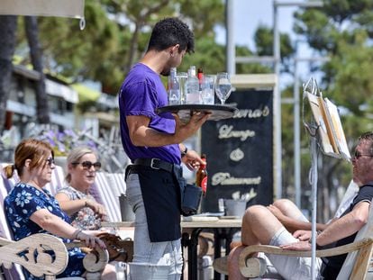 Un camarero atiende a unos clientes en la terraza de un restaurante del paseo marítimo de Platja d'Aro (Girona).
