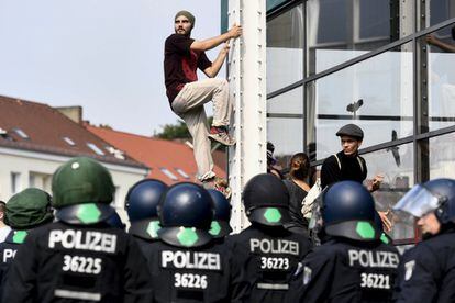 Un manifestante escala una estructura metálica ante la mirada de los agentes antidisturbios durante una protesta frente a la estación de Schlump de Hamburgo.