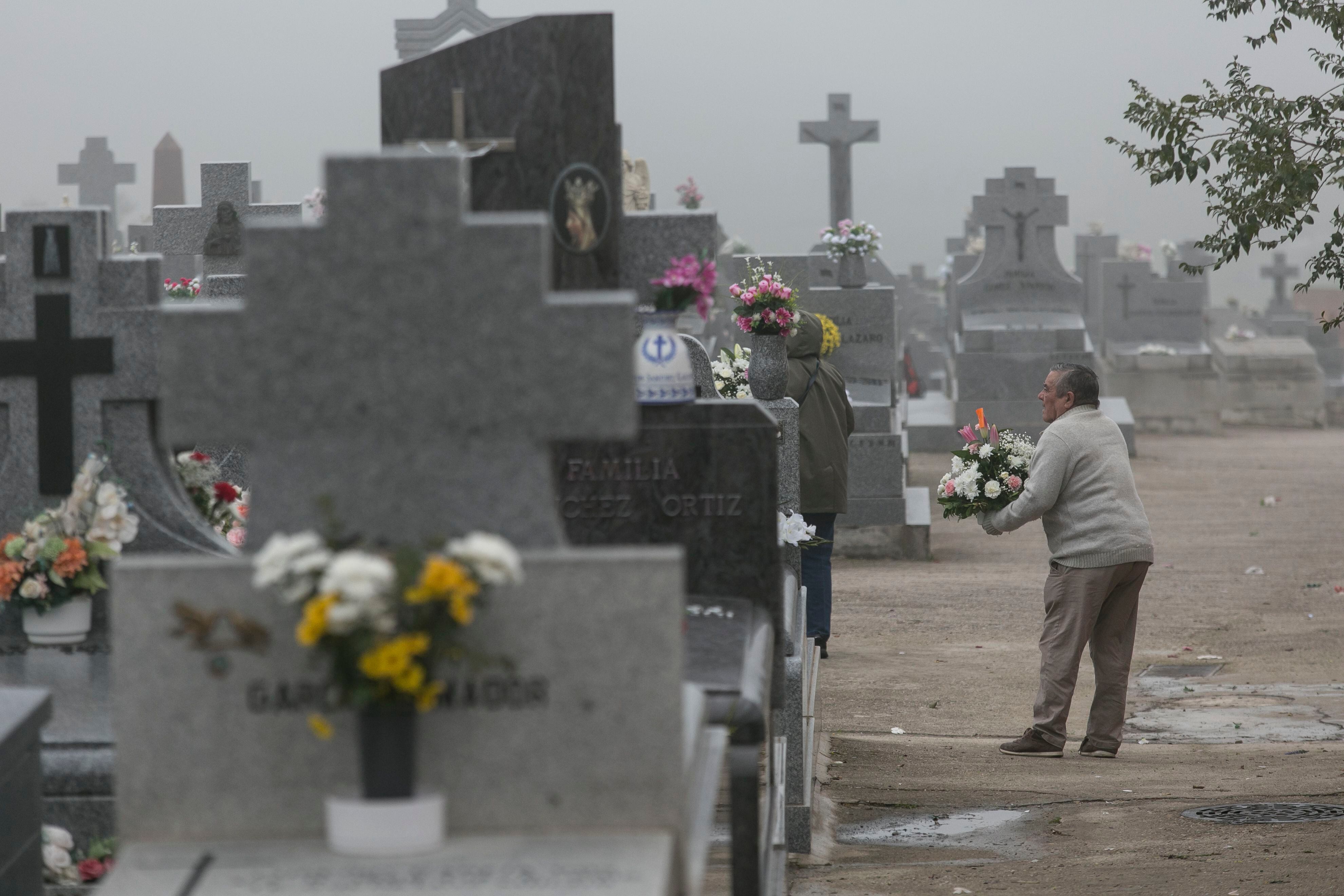 Un hombre deposita flores en el cementerio de Colmenar Viejo (Comunidad de Madrid) el Día de Todos los Santos.
