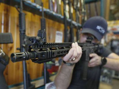 Un hombre sostiene un AR-15 en una tienda de armas.