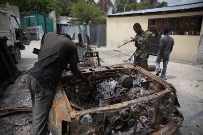 Un grupo de hombres trabaja para rescatar piezas de un automóvil que se incendió durante enfrentamientos entre bandas armadas en el barrio Butte Boyer, en Puerto Príncipe,  el 13 de mayo de 2022.