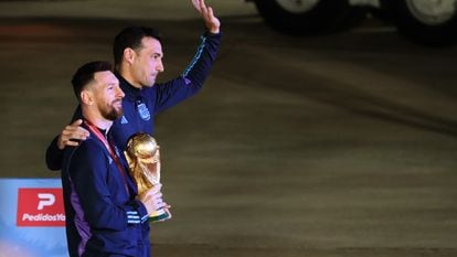 Lionel Messi de la selección argentina de fútbol saluda con el trofeo del Mundial de Fútbol Qatar 2022 junto al seleccionador Lionel Scaloni (d) a su llegada hoy, al Aeropuerto Internacional de Ezeiza a unos 22km de Buenos Aires (Argentina).